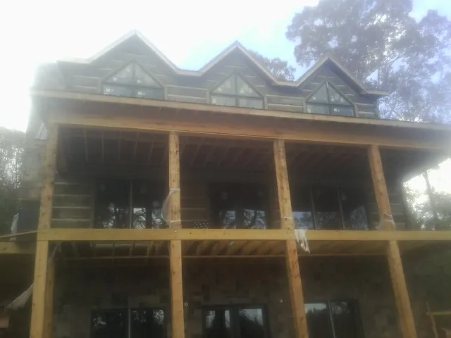 Dormers and porch framing on a large log home under construction — Roof Coating work by our crew in New London